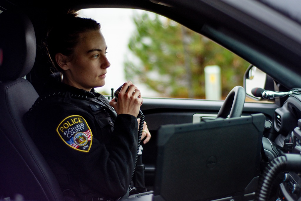 female officer on radio in police car.